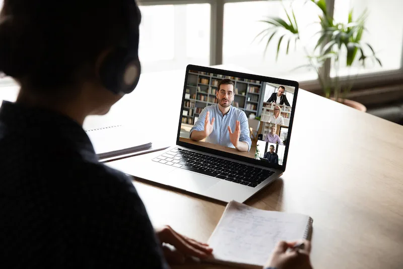 E-learning via virtual application, videocall video conferencing activity, colleagues working together concept. Pc screen view over woman shoulder, listen tutor gain new knowledge noting information